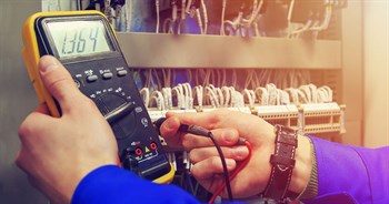 Closeup of electrician's hands as they use a meter and works with wiring