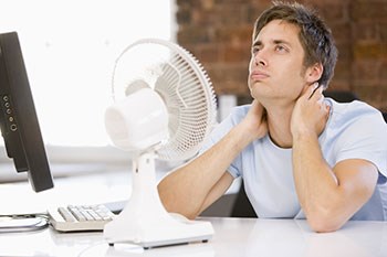 Man sitting at a desk with a desk fan