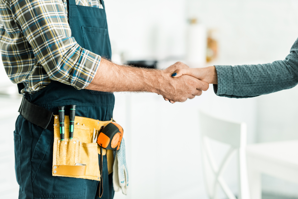 plumber and client shaking hands in kitchen